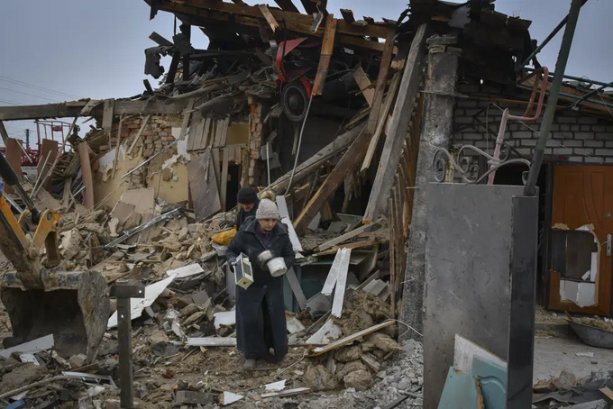 Personas cargan sus pertenencias al dejar sus casas destrozadas en el ataque con cohete ruso del sábado en Zaporiyia, Ucrania, el domingo 1 de enero de 2023. (AP Foto/Andriy Andriyenko